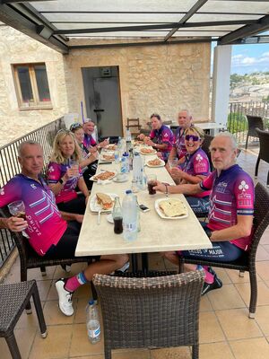 Cyclists sitting at a long table in a cafe